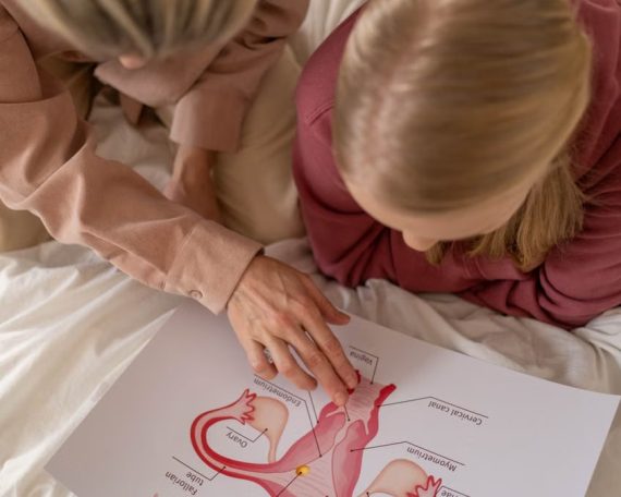 Mother and daughter studying reproductive system illustration for sex education at home.