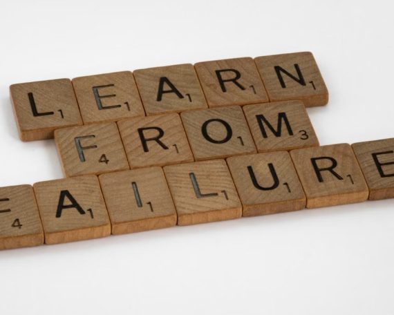 Wooden Scrabble tiles spelling 'Learn from Failure' on a white background, promoting resilience.